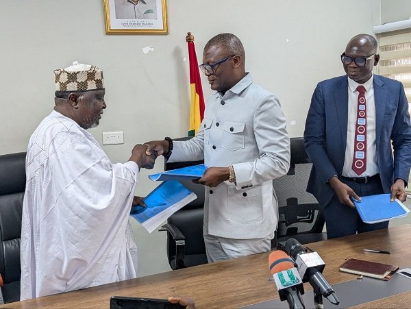 • Mr Kofi Adams and Mr Kalkaba Malboum exchanging copies of the document. Looking on is Mr Bawa Fuseini