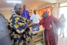 Mr Roland Ayoo(left), handing over an item to a beneficiary
