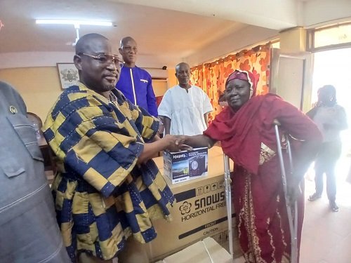 Mr Roland Ayoo(left), handing over an item to a beneficiary