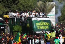 Senegal players and staff celebrate with the trophy on the bus during the victory parade
