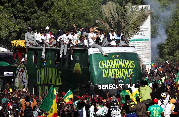 Senegal players and staff celebrate with the trophy on the bus during the victory parade