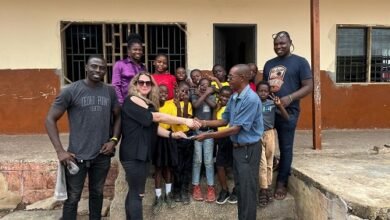 Mrs Addo presenting the cash to Ataa Lartey. Looking on are the husband of the donour, Mr Addo (left) and staff and children of the Academy