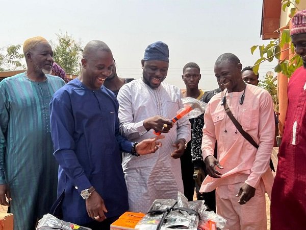 Alhaji Mahama (middle) presenting one of the equipment to a beneficiary
