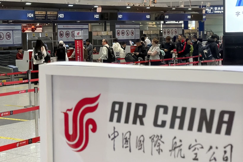 People line up in front of an Air China’s counter at Beijing Capital International Airport in Beijing yesterday for the direct flight