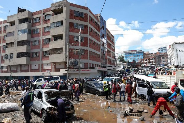 People stand around destroyed vehicles following flash floods caused by heavy rainfall in the Grogan area