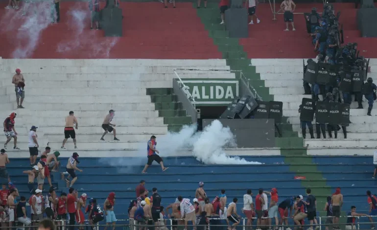 Fans of Cerro Porteno clash with police officers during their team’s match against Olimpia at the Defensores del Chaco stadium in Asuncion