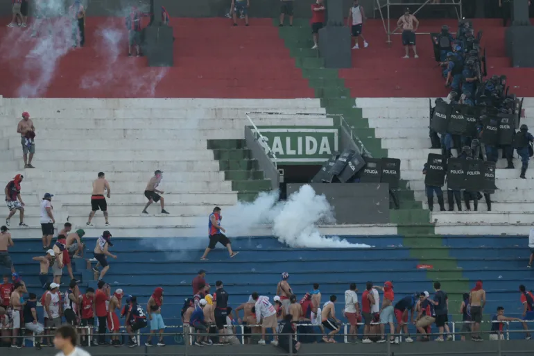 Fans of Cerro Porteno clash with police officers during their team’s match against Olimpia at the Defensores del Chaco stadium in Asuncion