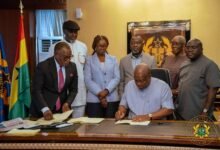 -President Mahama (seated) assenting his signature to the bills