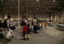 Special Immigrants from Afghanistan walk through the in-processing building after their evacuation at Camp As Sayliyah, Qatar