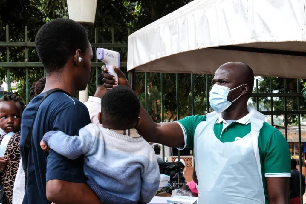 A health official uses a thermometer to screen people in front of a hospital