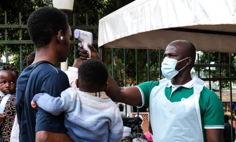 A health official uses a thermometer to screen people in front of a hospital