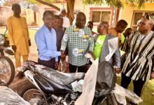 Mr Opoku (middle) handing over one of the motorbikes to a beneficiary