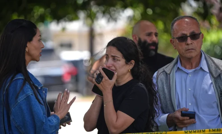 People stand behind police tape at the scene of a shooting outside the Islamic Center of San Diego
