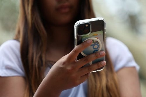A teenager poses holding a mobile phone