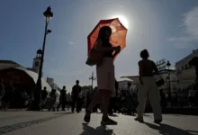 A woman with an umbrella walks at Plaza Puerta del Sol during a spring heatwave in Madrid, Spain