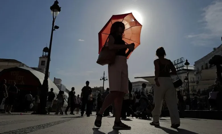 A woman with an umbrella walks at Plaza Puerta del Sol during a spring heatwave in Madrid, Spain