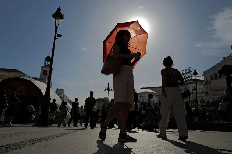 A woman with an umbrella walks at Plaza Puerta del Sol during a spring heatwave in Madrid, Spain