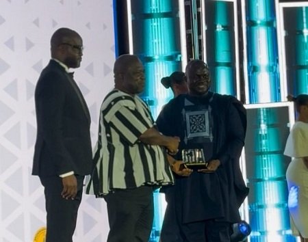 Mr Gunu (in smock) receiving the award from Mr Albert Kwabena Dwumfour, GJA President