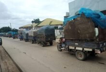 Loaded refuse tricycles waiting on the street to access the dumping site.