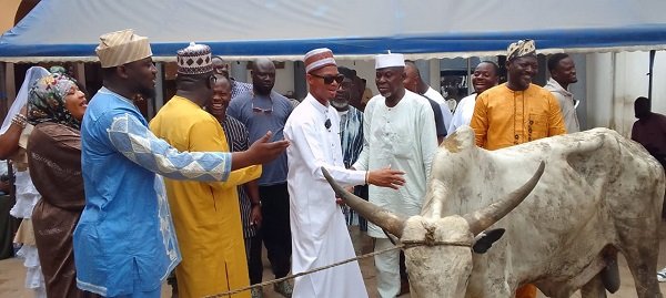 Dr. Sosu (middle) being assisted by Alhaji Faila (second from left) to present the cow