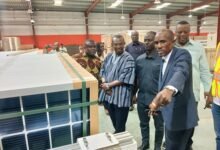 Mr Ocansey (in suit), explaining the manufacturing process to Mr Bedzrah (in smock) and other members of the committee
