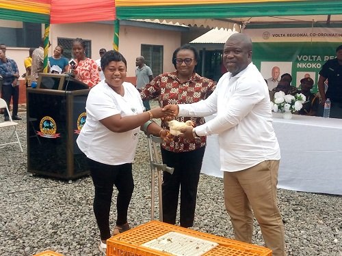 Mr Gunu (right) presenting four - week old chicks to a beneficiary at the launch