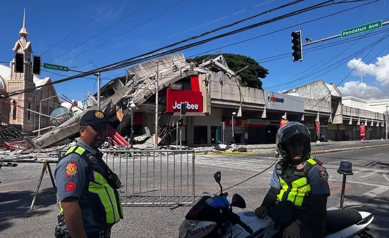 Police gather in front of a collapsed fast food restaurant after a magnitude 7.8 earthquake in General Santos City