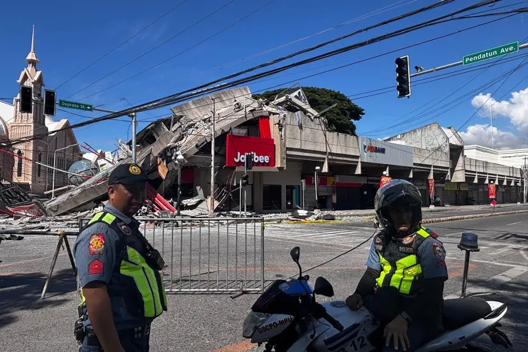 Police gather in front of a collapsed fast food restaurant after a magnitude 7.8 earthquake in General Santos City