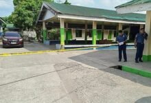 Police officers stand near the scene of a high school compound in Tacloban City, Philippines