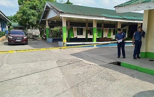Police officers stand near the scene of a high school compound in Tacloban City, Philippines
