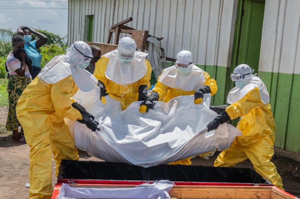 Red Cross workers place the body of a person who died of Ebola into a coffin at a health center in Rwampara, Congo