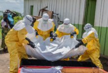 Red Cross workers place the body of a person who died of Ebola into a coffin at a health center in Rwampara, Congo