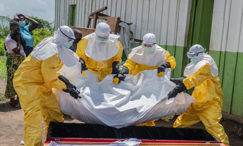 Red Cross workers place the body of a person who died of Ebola into a coffin at a health center in Rwampara, Congo