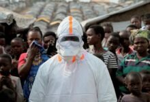 A health worker in personal protective equipment waiting for the burial of suspected Ebola victims