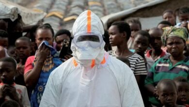 A health worker in personal protective equipment waiting for the burial of suspected Ebola victims