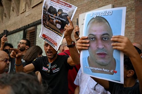A protester holds a flyer during a protest following the death of Abderrahim Fakir in Bologna, Italy