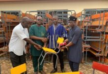 Mr Moabalyn (in smock) presenting the desks to GES officials