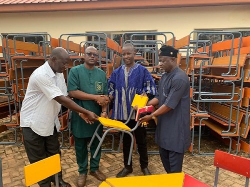 Mr Moabalyn (in smock) presenting the desks to GES officials