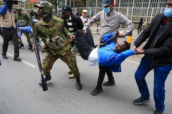 Kenyan police officers arrest a protester,