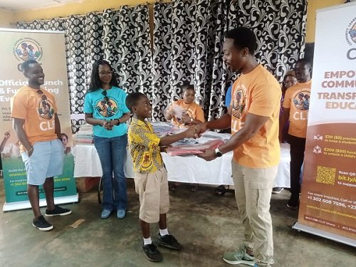 A beneficiary student receiving a backpack from Mr Laryea
