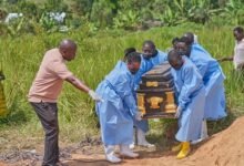 The coffin of an Ebola victim is carried to a gravesite