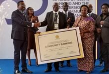 Dr Asiama (left) presenting Community Bank License to a representative of La Commuinity Bank ( second from right)