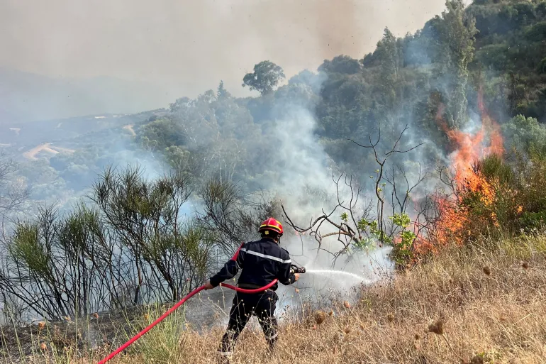 A firefighter works to extinguish a fire in Taourirt Ighil in the mountainous Bejaia province, Algeria