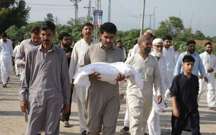 A man carries one of the body of a newborn baby for burial