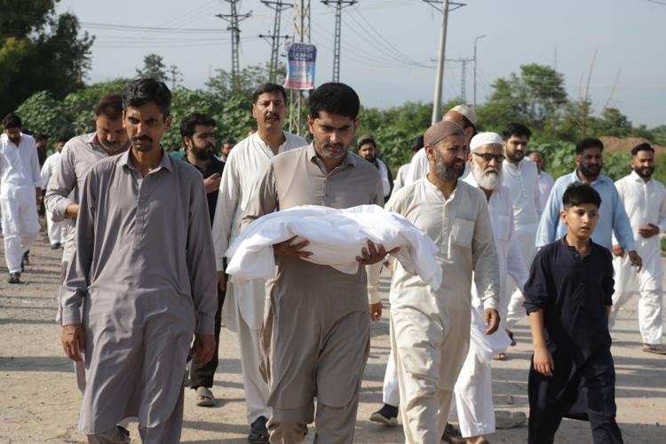 A man carries one of the body of a newborn baby for burial