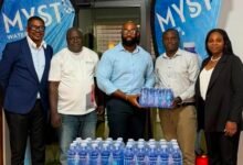 Mr Atitsogbui, Operations Manager at Medivents Consults receiving some of the water from the CEO of PNF Limited, producers of Myst Water