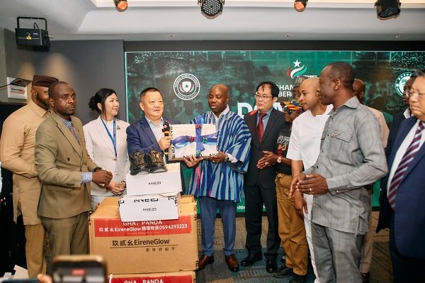 Mr Wei (right) presenting the items to Mr Deen while members from both sides look on