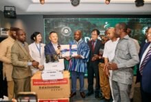 Mr Wei (right) presenting the items to Mr Deen while members from both sides look on