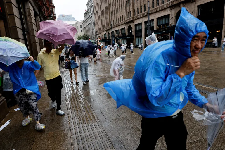 People use umbrellas and raincoats as winds intensify ahead of the arrival of Typhoon Dolphin in Shanghai, China