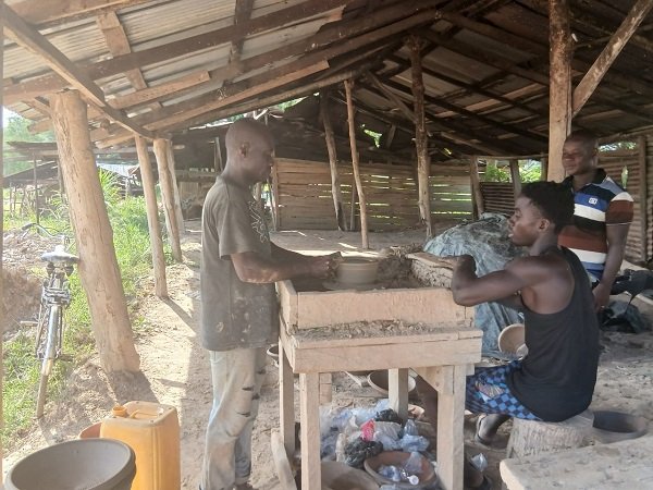 Abubakhar Alhassan (left) at his shop moulding earthenware at Tanoso